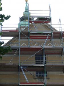 Dachfanggerüst an einem historischen Gebäude mit barocker Turmspitze, mehrlagiges Fassadengerüst zur Absturzsicherung am geneigten Dach.