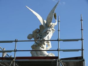 Skulptur mit Engelsfigur auf einem Arbeitsgerüst unter freiem Himmel während Restaurierungsarbeiten.