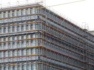 Fassadengerüst an einem mehrstöckigen Büro oder Wohngebäude mit durchgehenden Gerüstlagen zur Durchführung von Sanierungs oder Ausbauarbeiten.