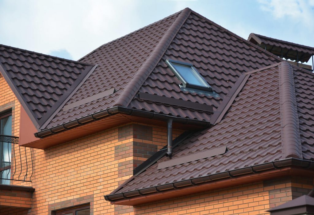 Haus mit rotem Ziegeldach, Dachfenster und deutlich sichtbarem, geschlossenen Dachkasten aus farblich passendem Material unter der Dachtraufe.