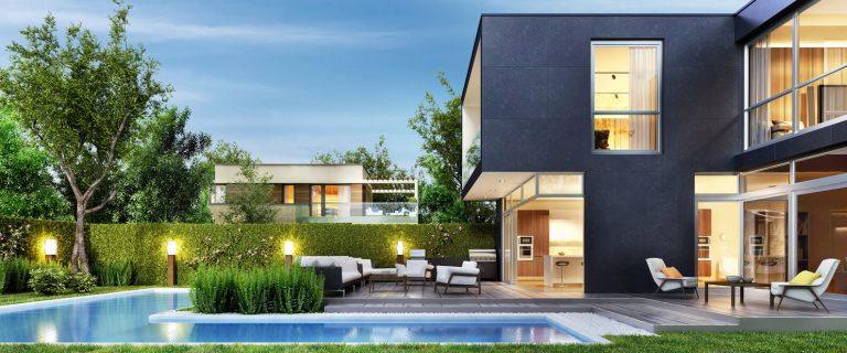Modernes Einfamilienhaus mit großflächigen Fenstern, stilvoller Holzterrasse, gepflegtem Garten und beleuchtetem Außenbereich mit Pool bei Abenddämmerung.