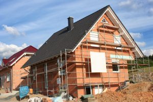 Fassadengerüst an einem Einfamilienhaus im Rohbau, vorbereitet für Fassadenarbeiten bei sonnigem Wetter.