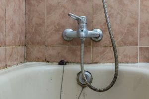 Verschimmelte Badewanne in einem Badezimmer mit alten verdreckten Fliesen