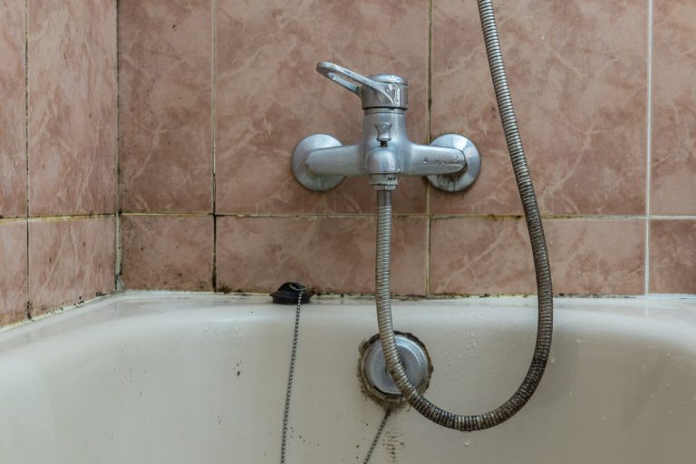 Verschimmelte Badewanne in einem Badezimmer mit alten verdreckten Fliesen