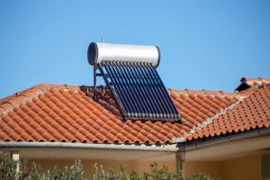 Eine Solarthermie mit Warmwasserspeicher auf einem Dach eines Hauses mit roten Ziegeln