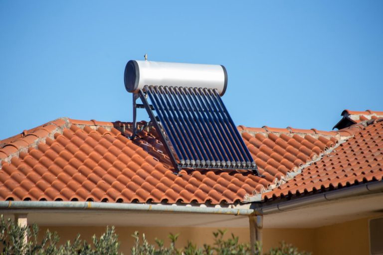 Eine Solarthermie mit Warmwasserspeicher auf einem Dach eines Hauses mit roten Ziegeln