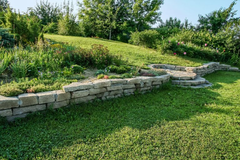 Terrassierter Garten mit Trockenmauer aus Naturstein zur Hangbefestigung, bepflanzt mit Blumen und Stauden.