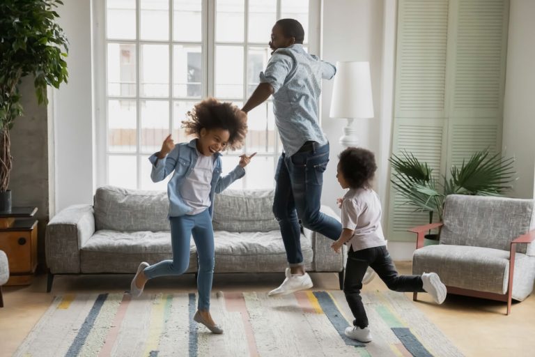 Familie springt im Wohnzimmer auf dem Holzboden herum