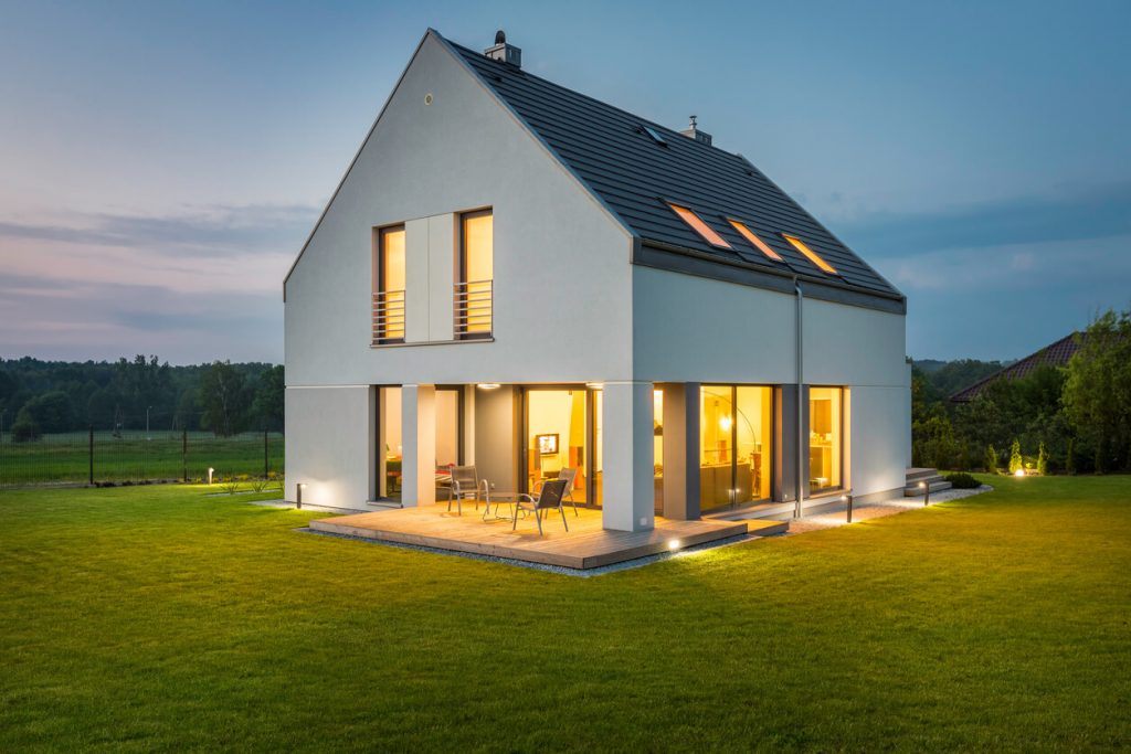 Modernes beleuchtetes Haus auf einer Grünfläche.