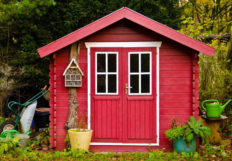 Rotes Gartenhäuschen mit Gartengeräten im Grünen