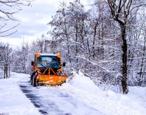 Schneepflug verrichtet in einer Schneelandschaft seine Artbeit.