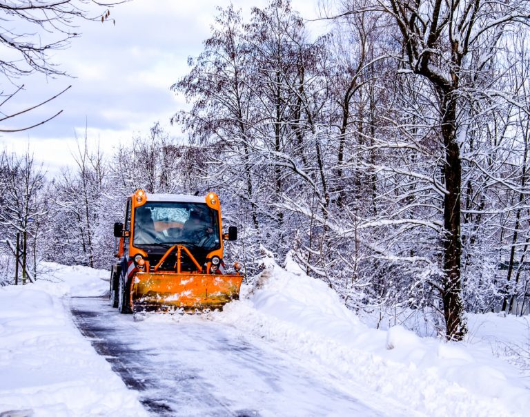 Schneepflug verrichtet in einer Schneelandschaft seine Artbeit.