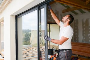 Handwerker installiert eine Schiebetür aus Glas.