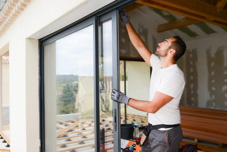 Handwerker installiert eine Schiebetür aus Glas.