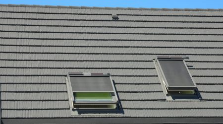 Hausdach mit Dachfenstern und Dachfenstermarkise als Sonnenschutz