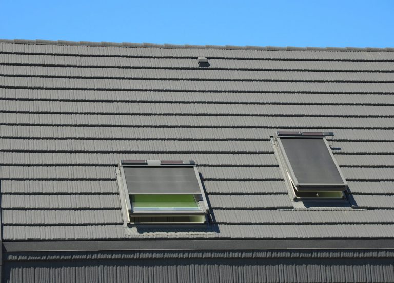 Hausdach mit Dachfenstern und Dachfenstermarkise als Sonnenschutz