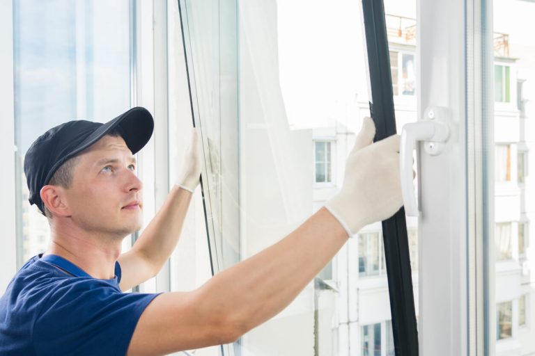 Mann baut neues Fenster ein
