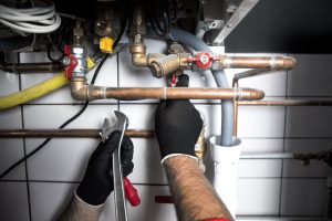 Klempner arbeitet mit Schraubenschlüssel an Wasserrohren