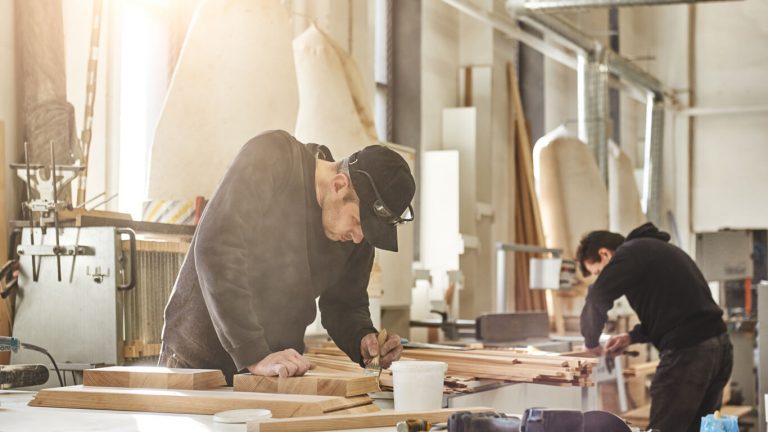 Tischler arbeitet an einer Werkbank an Möbelstücken
