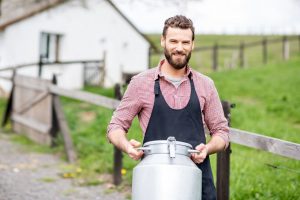 Landwirt trägt Milchkanne im Freien