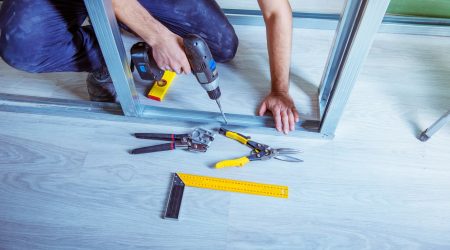 Handwerker bohrt in ein Trockenbauprofil aus Metall