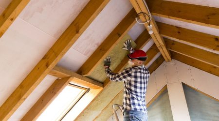 Dämmmaterial für die Dämmung des Dachs wird von Handwerker zeischen den Sparren angebracht