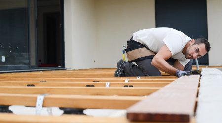 Handwerker gleicht Holzbalkendecke aus