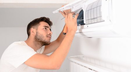 Mann installiert eine Lüftungsanlage an der Wand