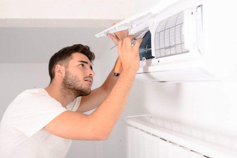 Mann installiert eine Lüftungsanlage an der Wand