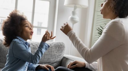 Mutter trainiert Mädchen mit Hand- und Fingergesten zu kommunizieren