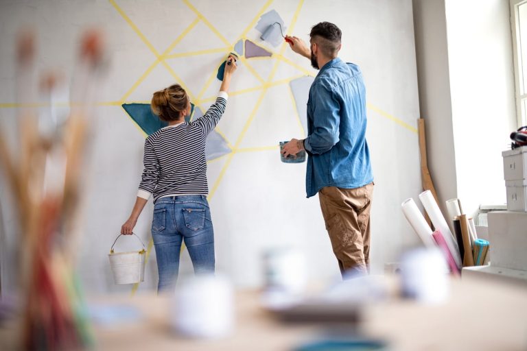 Eine Frau und eine Mann streichen gemeinsam eine vorbereitete Wand mit besonderer Technik in einer Wohnung