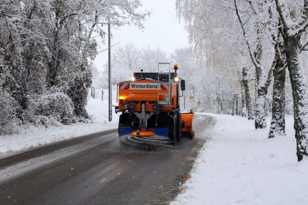 Winterdienst verteilt Streusalz mit einem Fahrzeug auf einer Straße