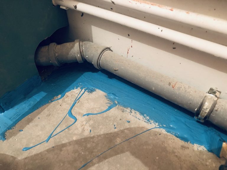 Blauer Dichtstoff zur Bodenabdichtung auf Fugen und Ecken unter Wasserrohren