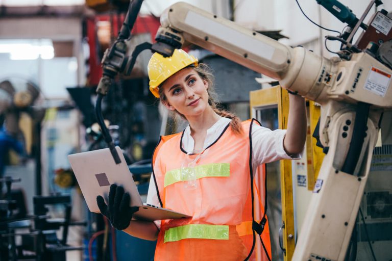 Frau mit Helm und Uniform mit Laptop-Kontrolle an Maschine