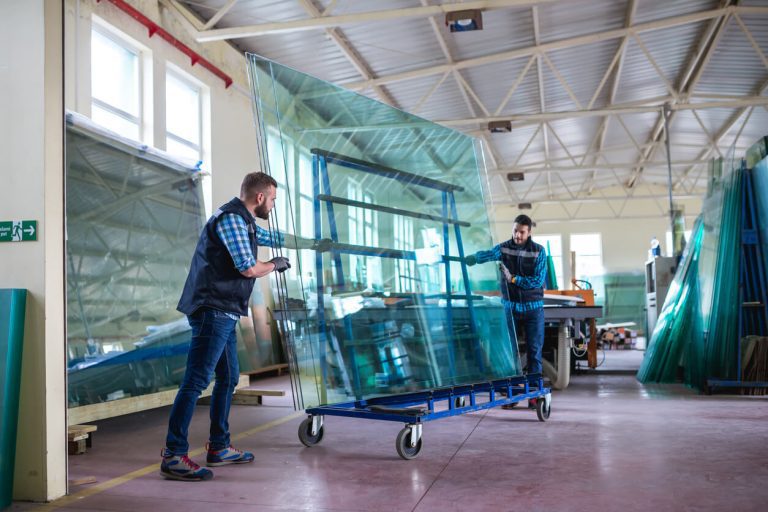 Zwei Männer schieben eine Glasplatte auf einem Rollbrett