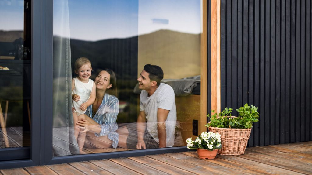 Familie sitzt im Haus vor einem großen Fenster