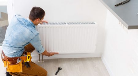 Mann montiert Heizkörper an einer Wand