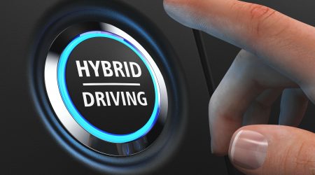 Hand drückt auf Knopf im Auto für Hybrides Fahren