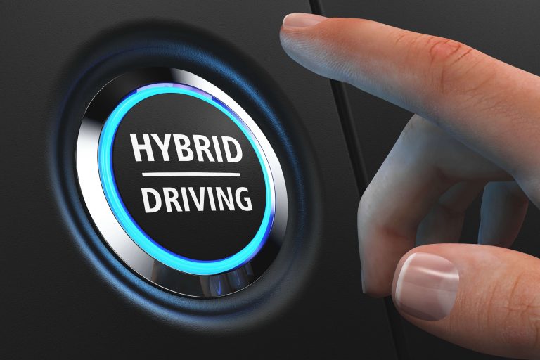Hand drückt auf Knopf im Auto für Hybrides Fahren