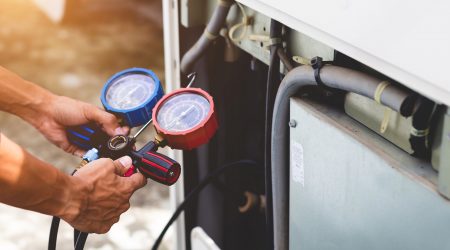 Mechaniker wartet Luftwärmepumpe mit einem Messgerät