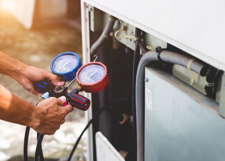 Mechaniker wartet Luftwärmepumpe mit einem Messgerät