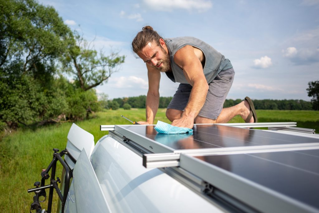 Mann reinigt Photovoltaik auf dem Dach eines Wohnwagens
