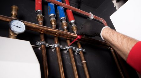 Sanitärinstallateur prüft Wasserleitungen in einer Wand
