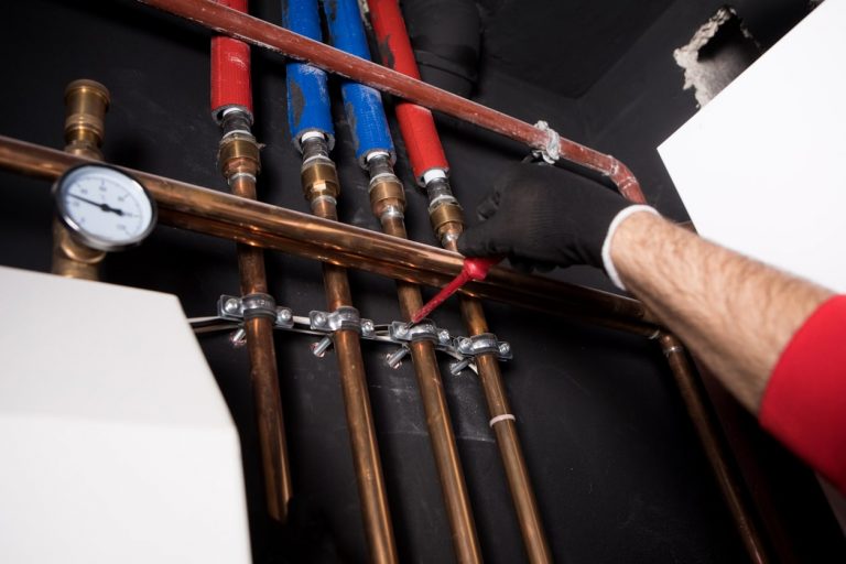 Sanitärinstallateur prüft Wasserleitungen in einer Wand