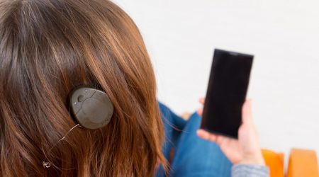 Frau mit Mittelohrimplantat mit Smartphone