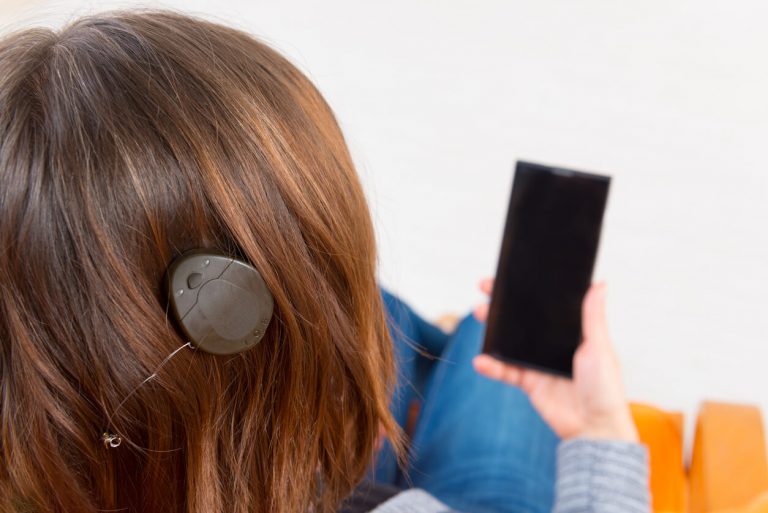 Frau mit Mittelohrimplantat mit Smartphone