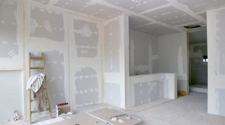 Baustelle mit verputzten Wänden und einer Leiter