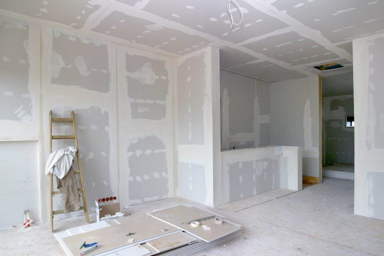 Baustelle mit verputzten Wänden und einer Leiter