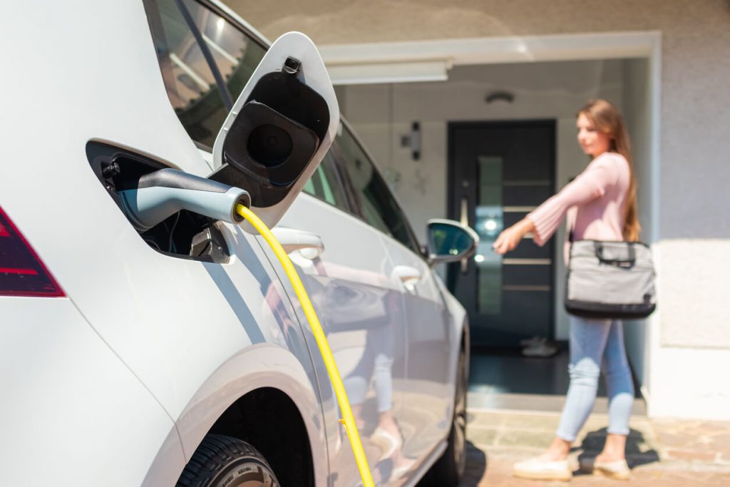 Frau lädt ihr Elektroauto zuhause mit Ladestation auf