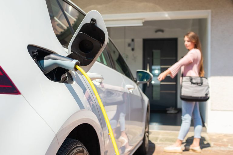 Frau lädt ihr Elektroauto zuhause mit Ladestation auf